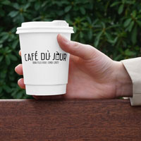 Kubek kawy Café du Jour w dłoni, gotowy do delektowania się kawą